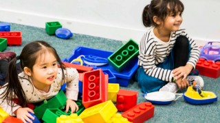 two small girls playing in a pile of giant lego